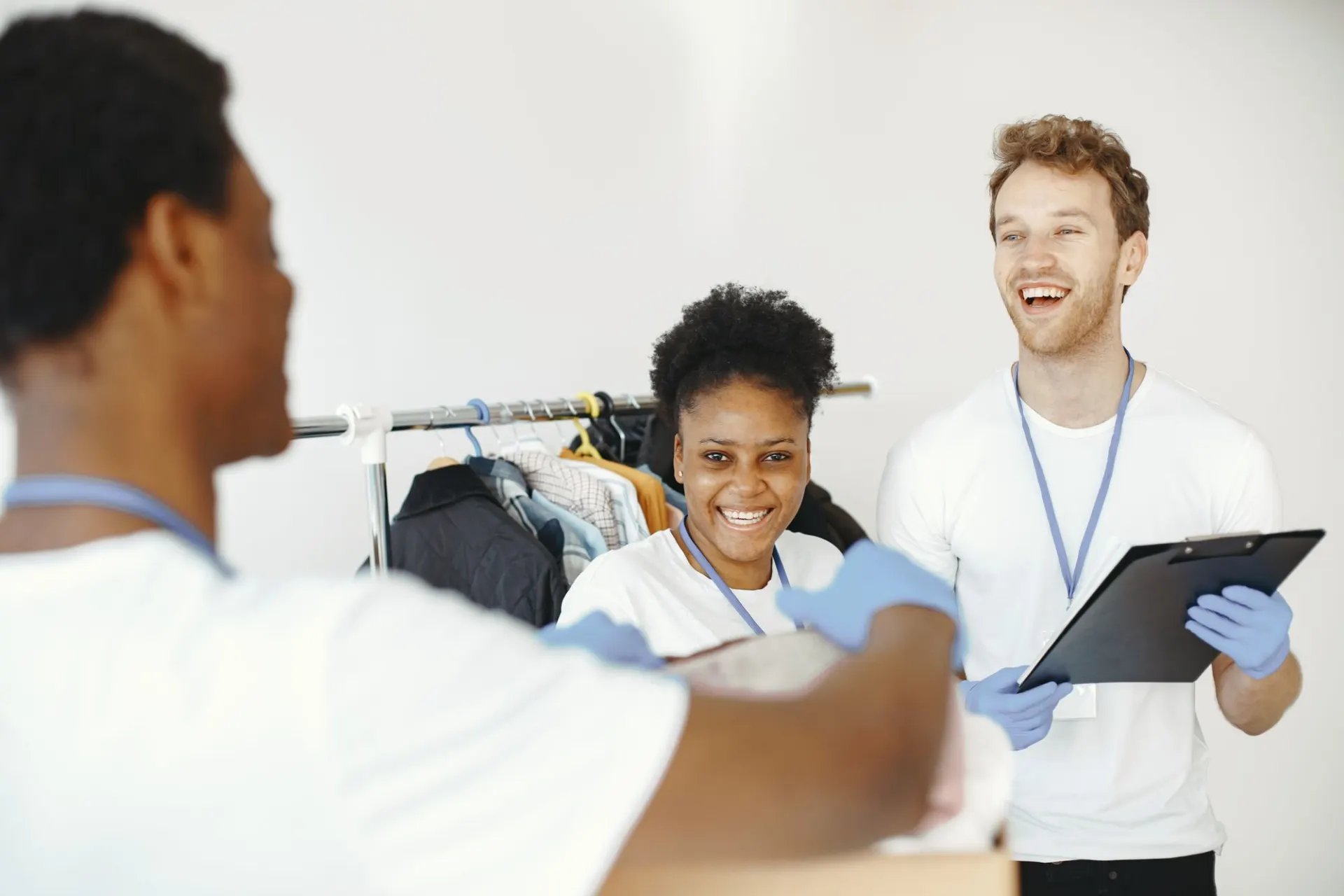 Drie vrijwilligers sorteren lachend gedoneerde kleding