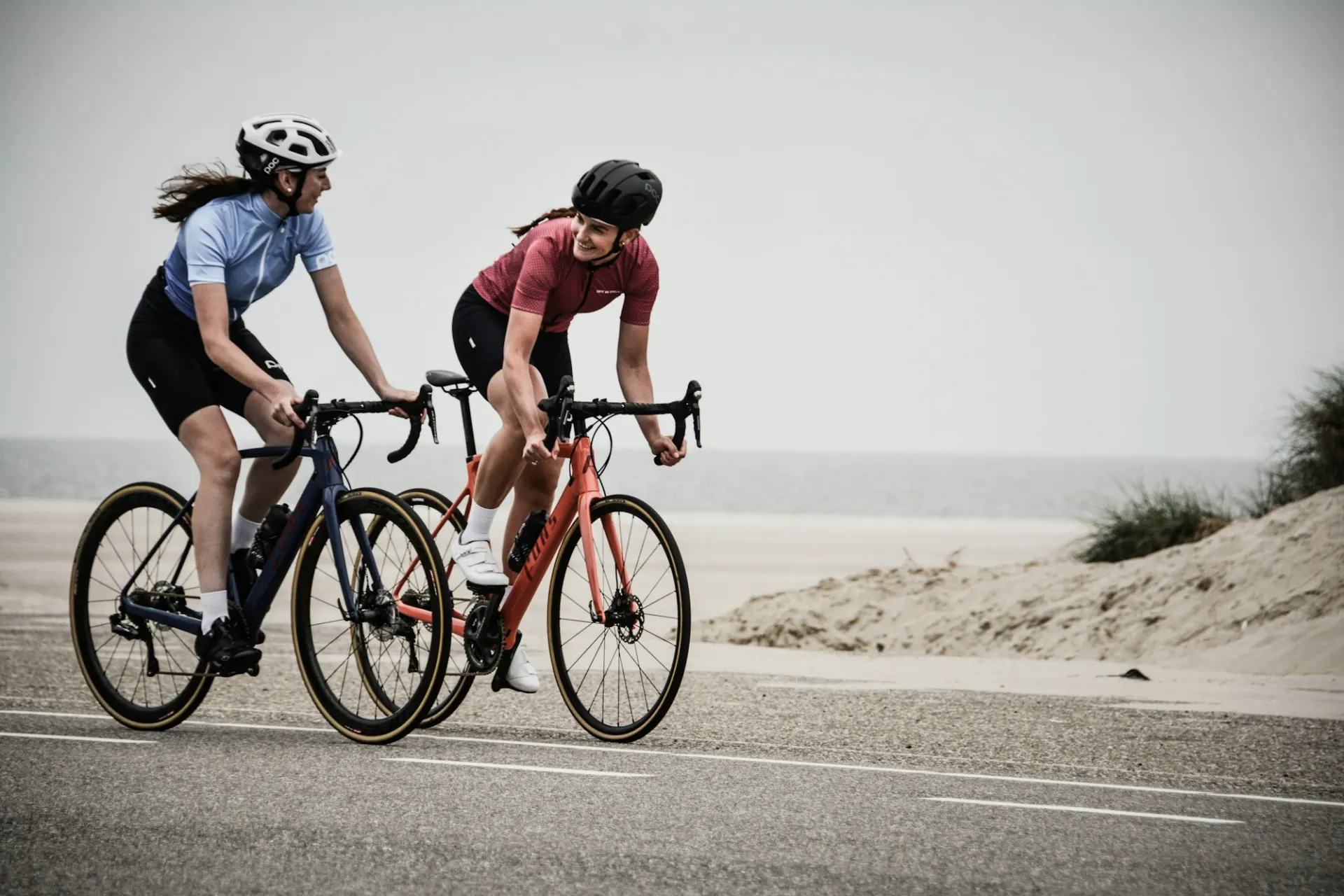 Twee wielrensters op racefietsen langs de duinen